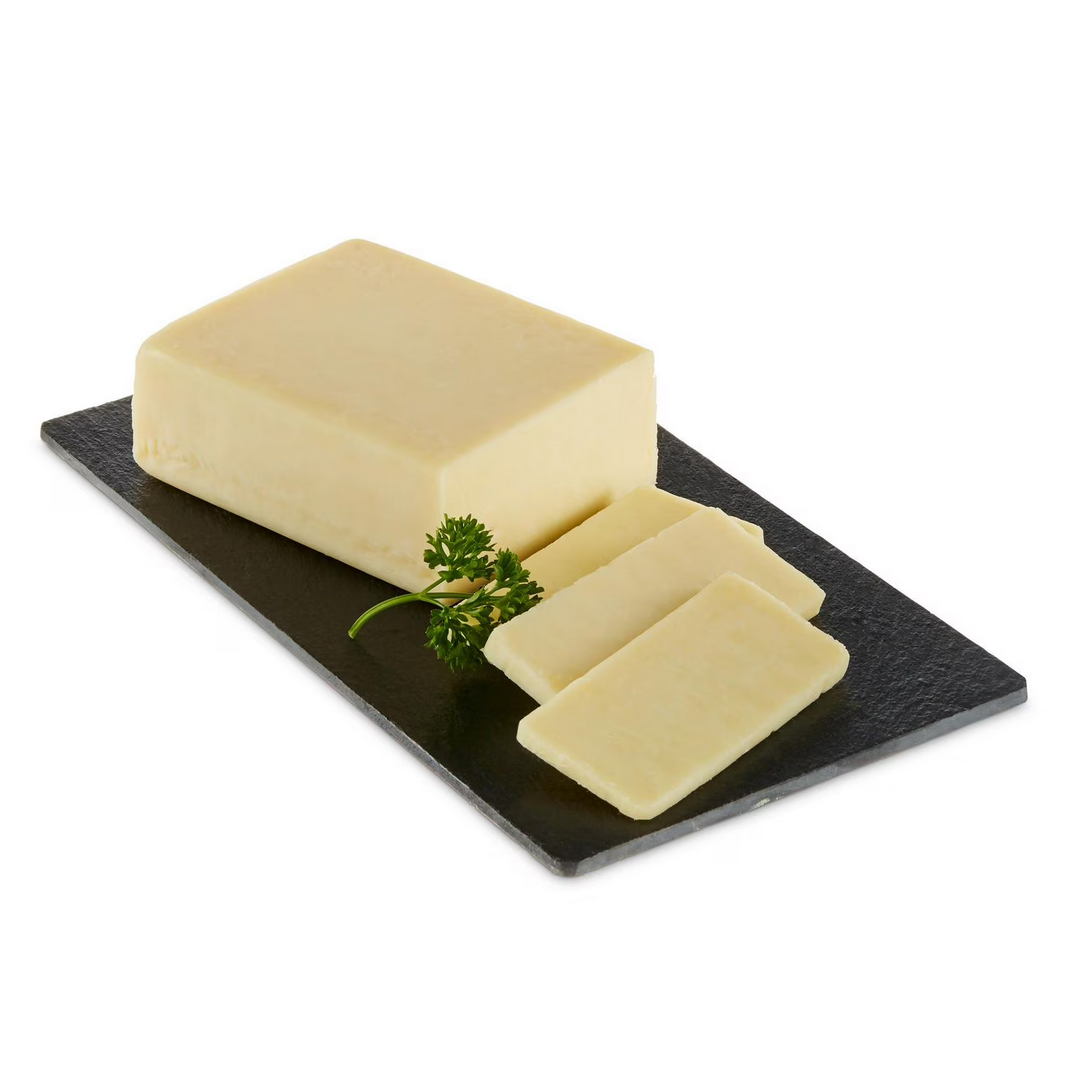 Block of Balderson Royal Canadian 2-year aged cheddar with slices on a black slate board garnished with fresh parsley.