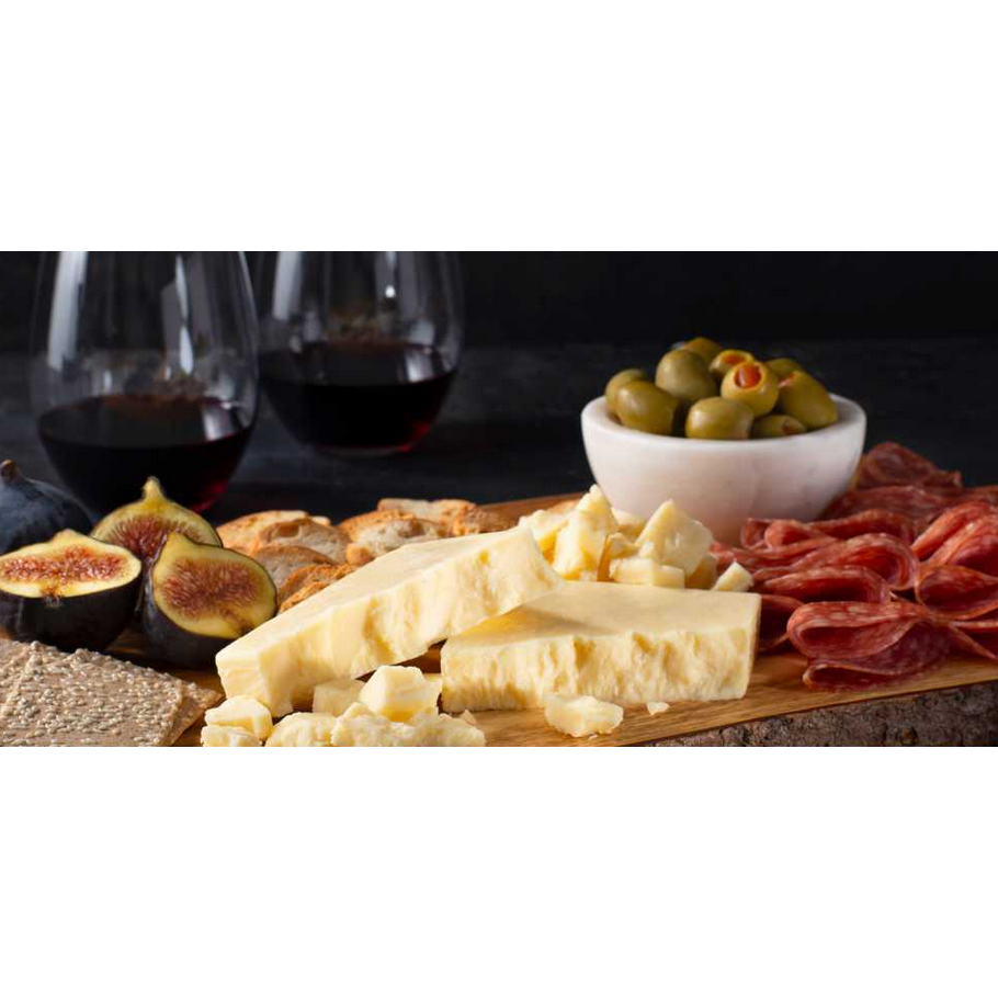 Balderson Royal Canadian cheddar wedges served on a wooden board with figs, salami, crackers, and red wine.